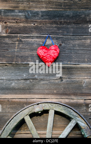 rotes Herzsymbol auf alte hölzerne Scheune Wand und Pferd Wagen Rad Stockfoto