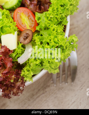 Closeup auf traditionelle griechische Salat in der Platte auf Holztisch mit Gabel, grünem Salat, frischem Gemüse serviert Stockfoto