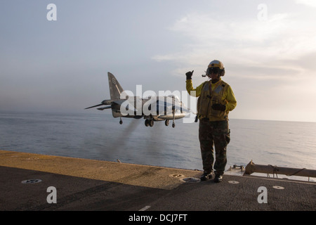 Luftfahrt Boatswain Mate (Handling) Airman Lucy Pizarro Signale wie ein AV-8 b Harrier vom amphibischer Angriff Schiff zieht Stockfoto