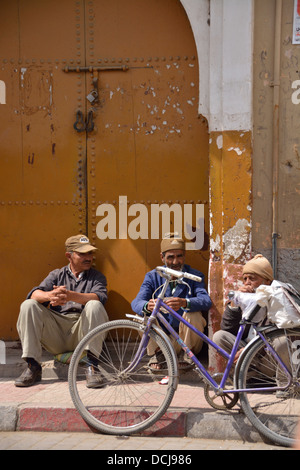 Drei Männer und ein Fahrrad gegenüber dem traditionellen geformte Tore.  Die alte walled Stadt von Taroudant, Marokko, Nordafrika. Stockfoto