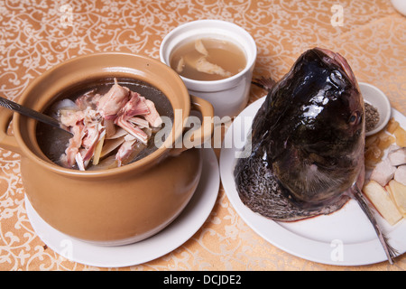 leckere Fischsuppe in Kasserolle und einen Fischkopf auf einem weißen Teller Stockfoto
