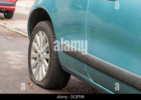 Reifenpanne. Auto mit einem platten Reifen am Straßenrand geparkt, England, Großbritannien Stockfoto