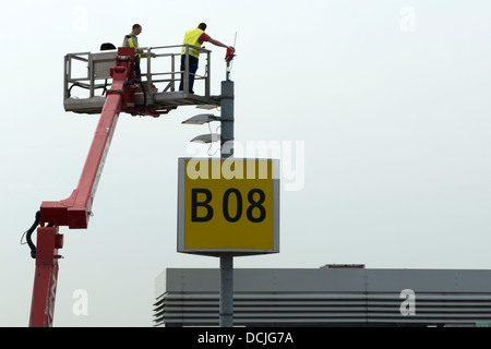 Arbeiter in einer Hubarbeitsbühne ersetzen Glühbirnen am Flughafen Düsseldorf Deutschland Stockfoto