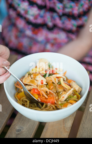 Chinesische Hähnchen Nudel unter Rühren braten, Frau aus einer Schüssel essen. Stockfoto