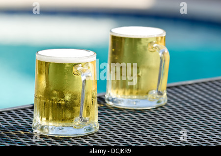 Zwei Biergläser auf dem Tisch von blauen Swimmingpool an einem sonnigen Sommertag Stockfoto