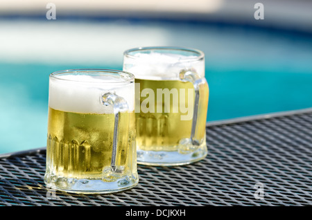 Zwei Biergläser auf dem Tisch von blauen Swimmingpool an einem sonnigen Sommertag Stockfoto