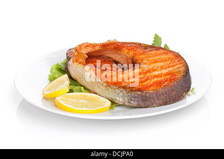 Gegrillter Lachs mit Zitronenscheiben und Kräutern auf Platte. Isoliert auf weißem Hintergrund Stockfoto