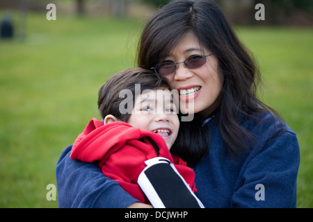 Schöne asiatische Mutter halten ihres behinderten Sohnes im park Stockfoto