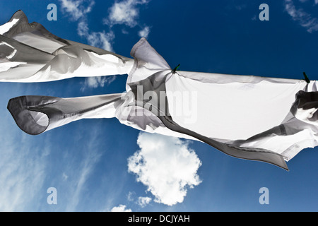 Weiße Hemden trocknen auf eine Wäscheleine mit blauen Himmel im Hintergrund Stockfoto