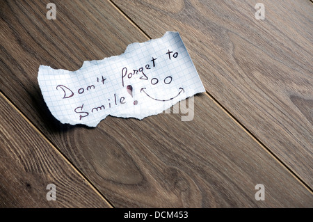 Vergessen Sie nicht, Smile - Hand, Schreiben von Text auf einem Blatt Papier auf Holz Hintergrund mit Platz für text Stockfoto