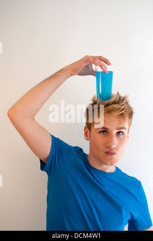 Junger Mann, ein Glas blau Erfrischungsgetränk auf seinen Kopf. Stockfoto