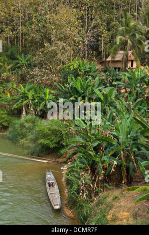 Vertikale Ansicht der Ramshackled Hütte und Fischerboot an den Ufern des Nam Song Flusses in der Nähe von Vang Vieng Stockfoto