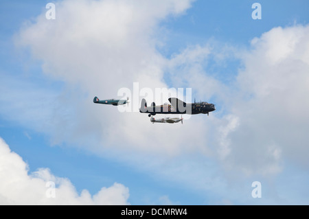 Horizontale Ansicht eines Lancaster-Bomber, flankiert von zwei Spitfires fliegen in den Himmel. Stockfoto