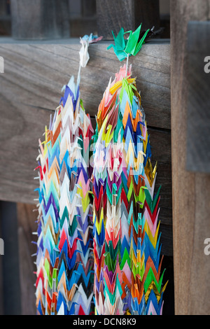 Zwei Ketten aus bunten Papierkraniche hängen von einer Holztür in einem Tempel in Japan. Stockfoto