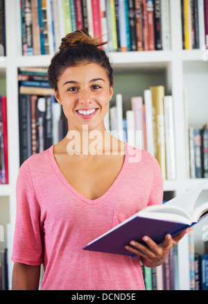 schöne glückliche junge Frau, die ein Buch in einem Wohnzimmer zu Hause Stockfoto