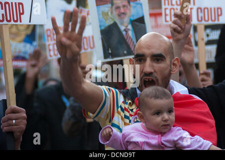 London, 20.08.2013. Ein Mann, der sein Baby hält Gesänge Parolen vor der ägyptischen Botschaft im Zuge der anhaltenden Proteste gegen die militärische Übernahme des gestürzten Präsidenten Morsi demokratisch gewählte Regierung. Stockfoto