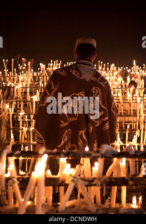 Ein Mann Lichter Kerzen im Votiv Room den Schrein der Jungfrau von Rocio in El Rocio, Andalusien, Spanien. Stockfoto
