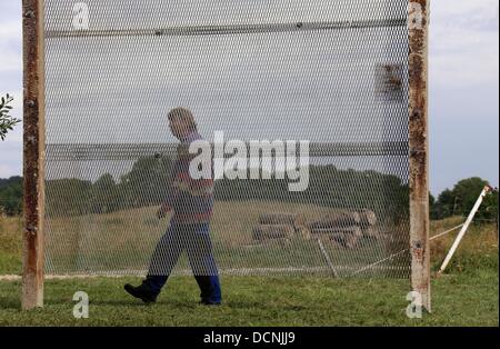 Eine Frau geht das erste Denkmal in Mecklenburg-Vorpommern für Opfer des inneren deutschen Grenze auf dem ehemaligen Todesstreifen in der Nähe von Kneese, Deutschland, 19. August 2013 Vergangenheit. Drei Jahrzehnte nach der Tod von Harry Weltzin Denkmal Form original Partss der ehemaligen Grenzanlagen mit einer Cermeony am 31. August 2013 eingeweiht werden. Foto: JENS Büttner Stockfoto