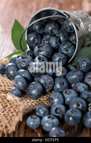 Einige Heidelbeeren in einen kleinen Eimer auf hölzernen Hintergrund (Makroaufnahme) Stockfoto