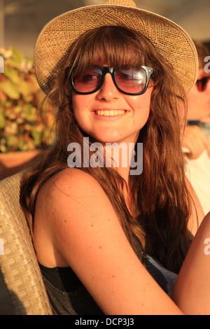 Hübsche Teenager-Mädchen mit Sonnenhut und Sonnenbrille, als die Sonne untergeht Stockfoto