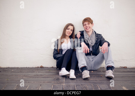Teenager-Paar sitzt an der Wand Stockfoto