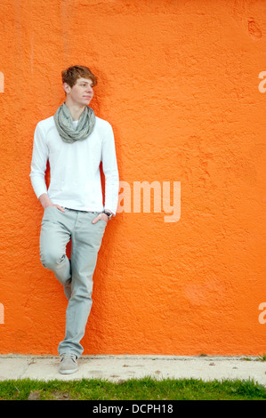 Coole junge Mann stehend durch die orange Wand Stockfoto