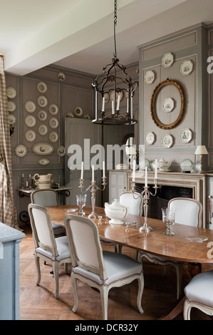 Französisch antike Stühle und Tisch im eleganten Speisesaal mit hölzernen Wandverkleidung und dekorativer Porzellanteller Stockfoto