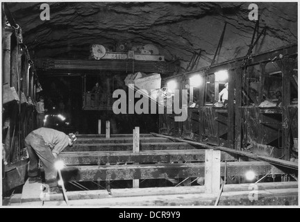 Diese Abbildung zeigt einen Traveler-Kran, der eine Kippschaufel oben auf den Seitenwandformen im Umlenktunnel Nr. 2 handhabt. Beton wird abgeladen, um den Bau des Tunnels zu unterstützen. Stockfoto