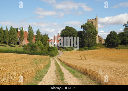 Feldweg durch Weizenfelder zur Erntezeit, Oast House und St-Margarethen Kirche, Horsmonden Kent England UK Stockfoto