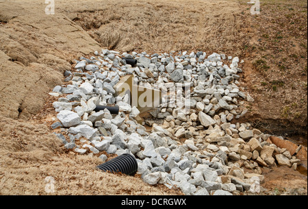 Schottersteine auf Beton- und Überlauf fließt aus einem See Stockfoto