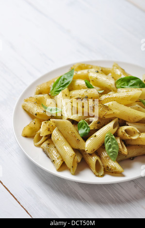 Penne-Nudeln mit Pesto-Sauce und Basilikum auf weißen Teller Stockfoto