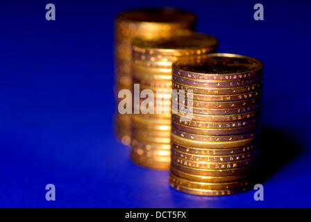 Mehrere Stapel von Goldmünzen auf blauem Hintergrund Stockfoto