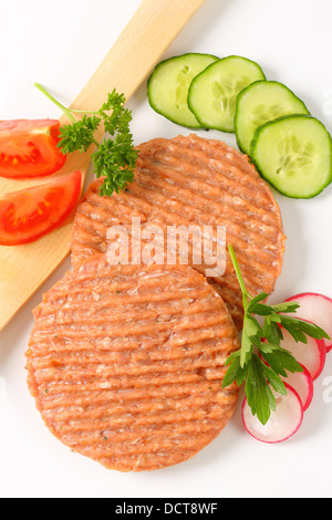 Studioaufnahme von Roh Burger Bratlinge und geschnittenem Gemüse Stockfoto