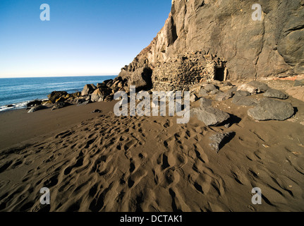 Fußspuren im Sand führenden Weg in Richtung Felsen und Gebäude aus Stein Stockfoto