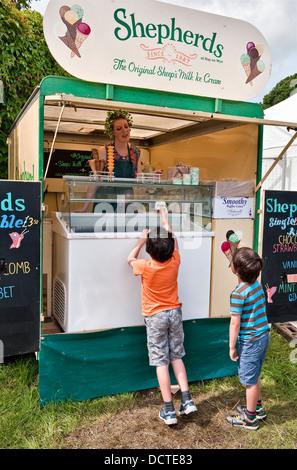 Kinder, die beim jährlichen Green man Musikfestival in Glanusk, Crickhowell, Wales, Großbritannien, Schaf-Milch-Eis am Shepherds Stand kaufen Stockfoto
