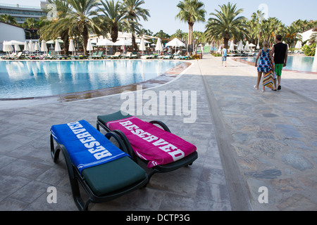 Zwei Sonnenliegen mit "reserviert" Handtücher neben einem Hotel-Schwimmbad Stockfoto