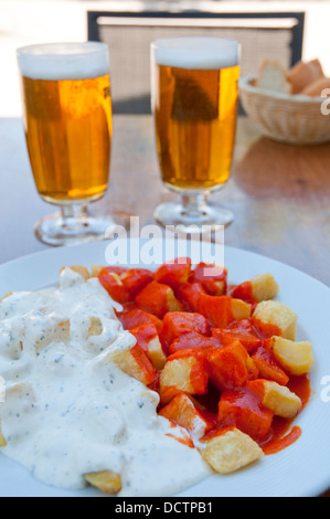 Spanische Vorspeise: Alioli und Bravas Kartoffeln mit zwei Gläsern des Lagers in eine Sommerterrasse. Madrid, Spanien. Stockfoto