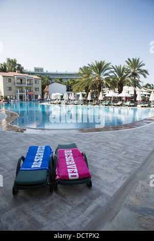 Zwei Sonnenliegen mit "reserviert" Handtücher neben einem Hotel-Schwimmbad Stockfoto