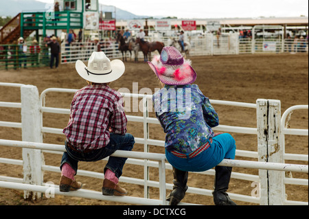 Junge & Mädchen gehockt Corral Zaun beobachten das Chaffee County Rodeo Stockfoto