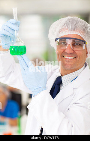 lächelnd leitenden medizinischen Forscher hält ein Fläschchen im Labor Stockfoto