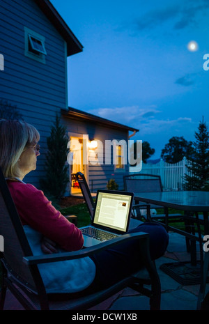 Frau in Heimarbeit auf Laptop-Computer in der Abenddämmerung Stockfoto