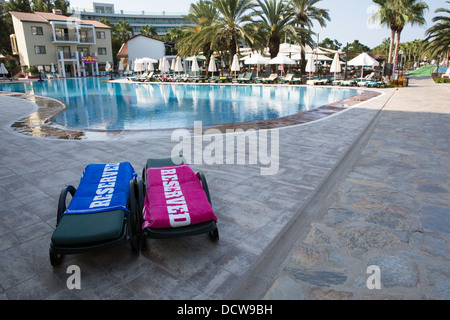 Zwei Sonnenliegen mit "reserviert" Handtücher neben einem Hotel-Schwimmbad Stockfoto