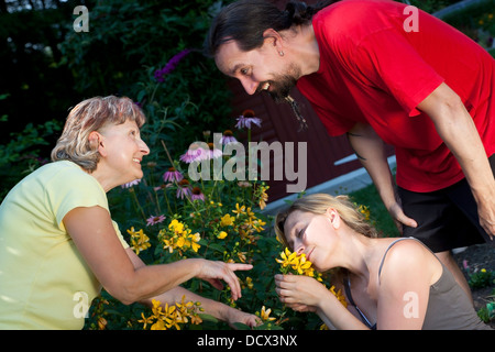 ältere Frau zeigt ein Paare Blumen im Garten Stockfoto
