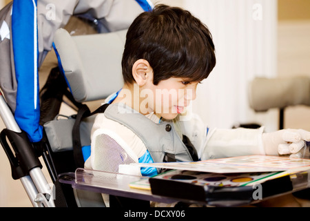 Vier Jahre alten junge studieren oder lesen im Rollstuhl deaktiviert Stockfoto