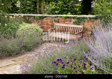 Sitzbank aus Holz im Garten, umgeben von Blumen Stockfoto