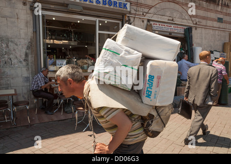 Mann trägt schwere Last auf seinem Rücken, Eminonu, Golden Horn, Istanbul, Türkei Stockfoto