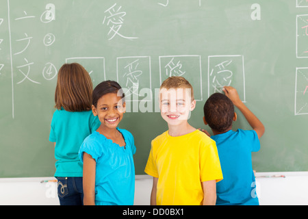 fröhliche Grundschüler nach dem Chines an Tafel schreiben Stockfoto