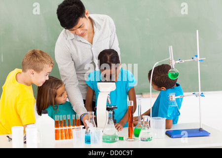 PV-Lehrerin und Schüler im naturwissenschaftlichen Unterricht mit jungen Mädchen mit Mikroskop Stockfoto