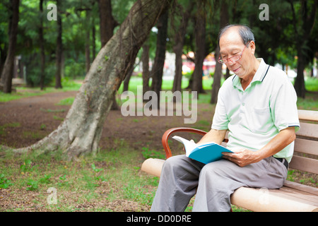 glücklicher senior Mann auf der Bank sitzen und Buch Stockfoto