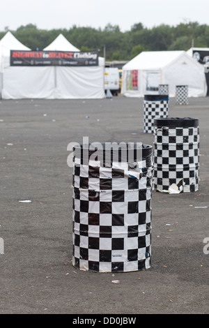 Leere Mülltonnen in einer Linie auf einem Festival mit Zelten im Hintergrund Stockfoto